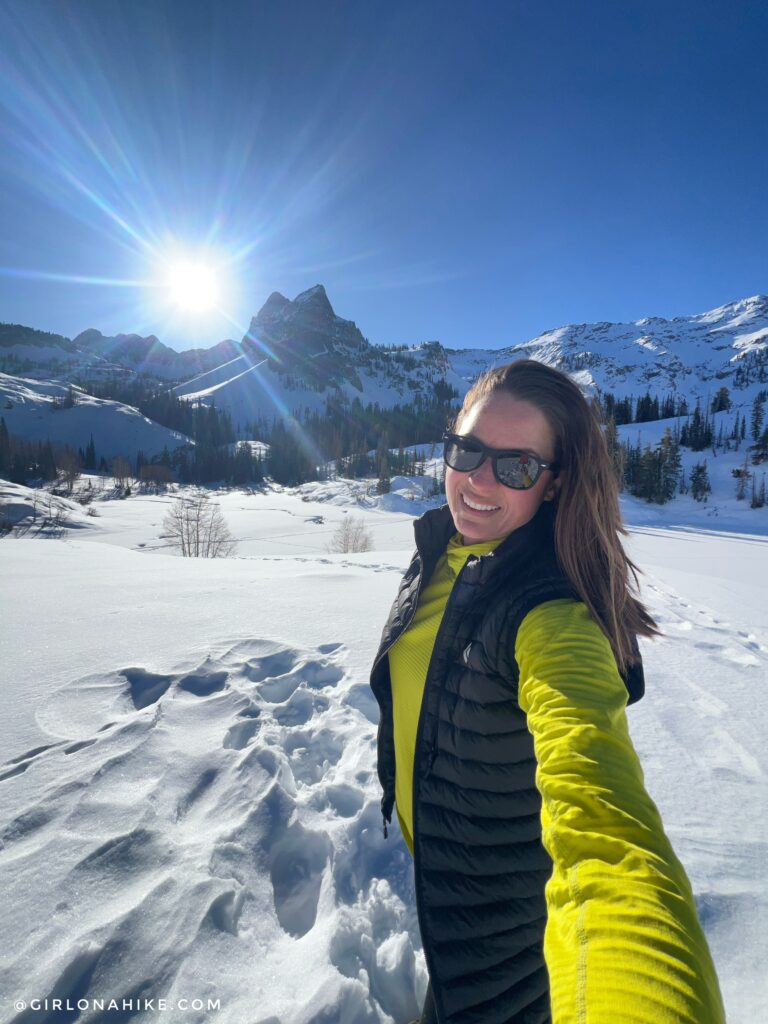 Hiker resting beside Lake Blanche while enjoying mountain views and sunshine